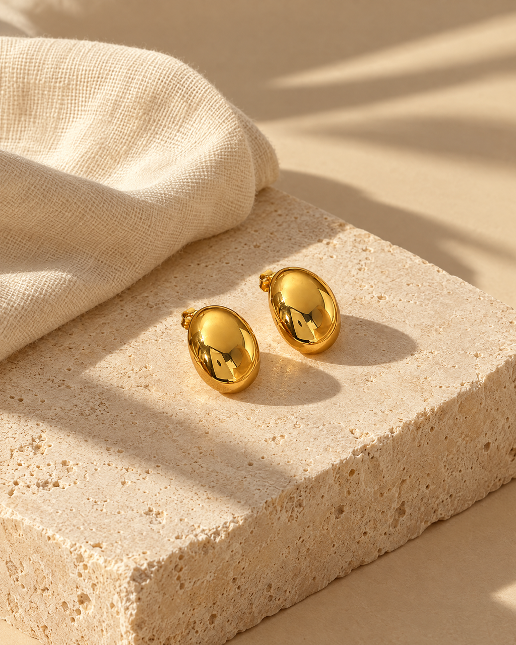 Gold dome earrings on travertine stone