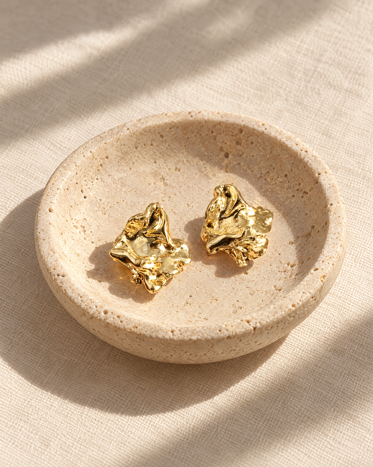 Molten gold studs in a travertine dish